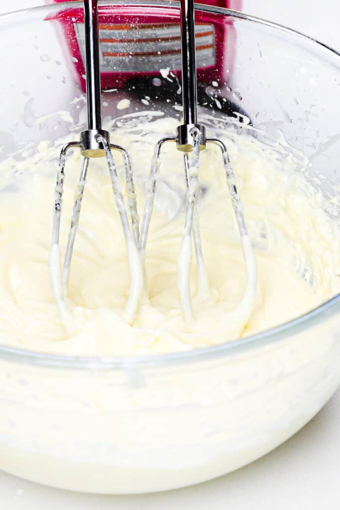 the mixed cream cheese icing in a bowl with beaters