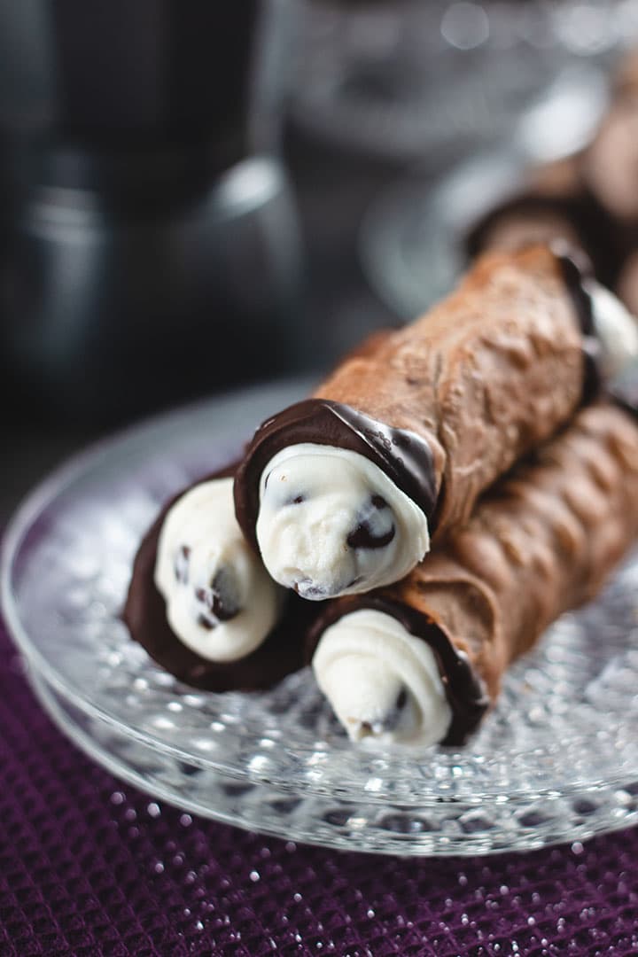 Homemade Cannoli filled and stacked on a crystal plate