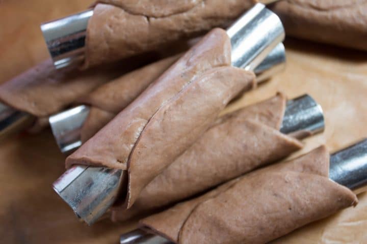 A bunch of cannoli tubes with the dough rounds wrapped around them
