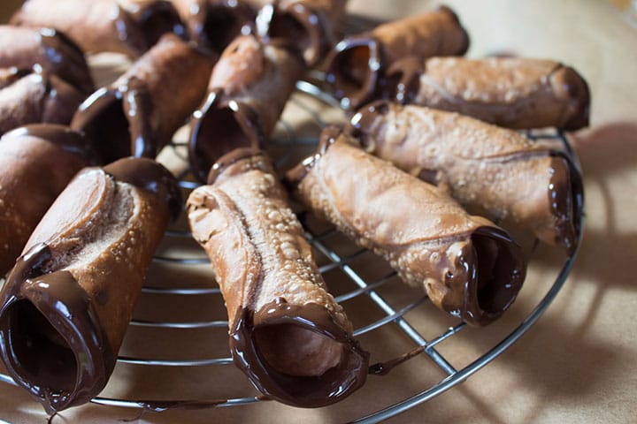 Chocolate dipped cannoli shells on a cooling rack