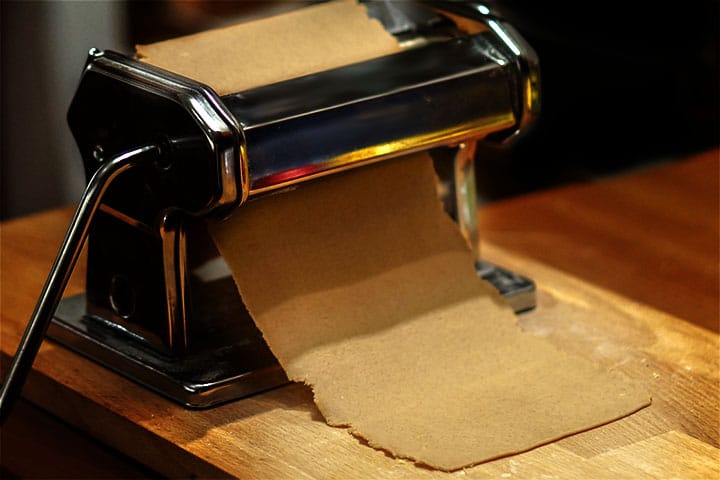 A pasta machine running the cannoli dough through it.