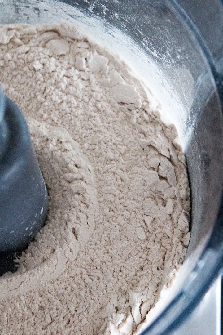 a close up of a food processor bowl with dry ingredients mixed thoroughly together