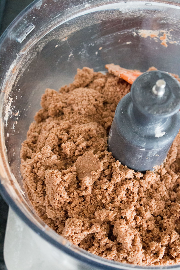 a close up of a food processor bowl with the wet ingredients mixed into the dry