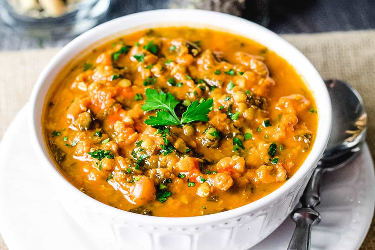 A bowl of lentil soup with fresh herb garnish