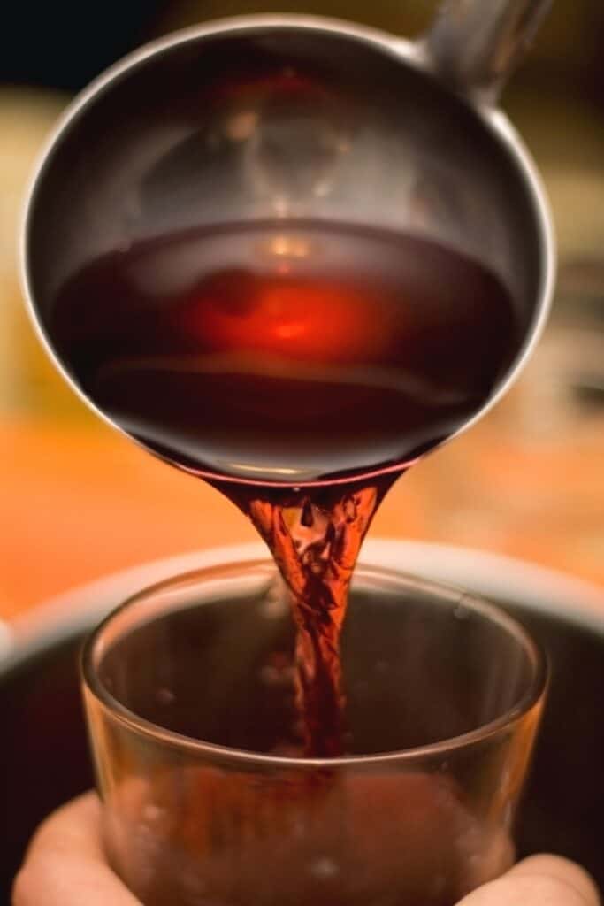 warm Cranberry Holiday Cocktail with Vodka being ladled into a glass mug