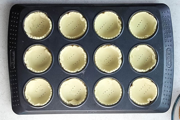 The dough circles added to the pan and docked with fork marks in the bottom