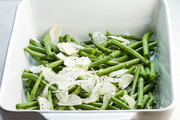 Garlic olive oil and seasoning added to the green beans in a pan