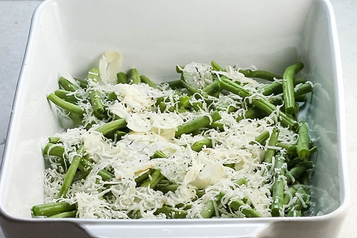 Parmesan cheese added to the Garlic olive oil and seasoning added to the green beans in a pan