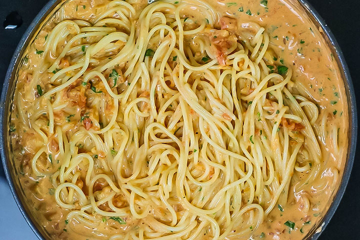 The pasta added to the pan with the sauce