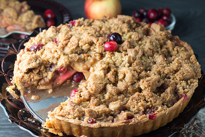 apple cranberry crumb pie with a piece cut out of it showing the fruit filling