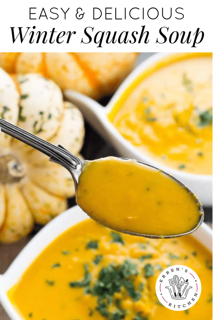A creamy bowl of orange, winter squash soup topped with fresh parsley and a big spoonful of soup taken out of the bowl. There are squashes on the table next to the bowl of soup.