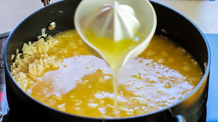 The lemon juice being added to the rice mixture in the pan