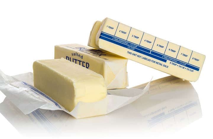 Four sticks of salted butter with one showing tablespoon markers 