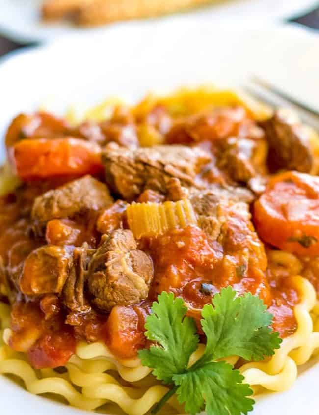 Italian Lamb stew in a plate on a bed of pasta