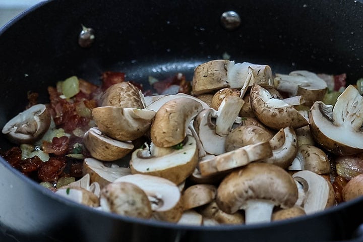 The mushrooms added to the pan with the bacon mixture.