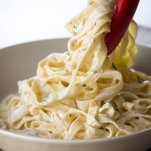 The Best Fettuccine Alfredo of Your Life being served with tongs