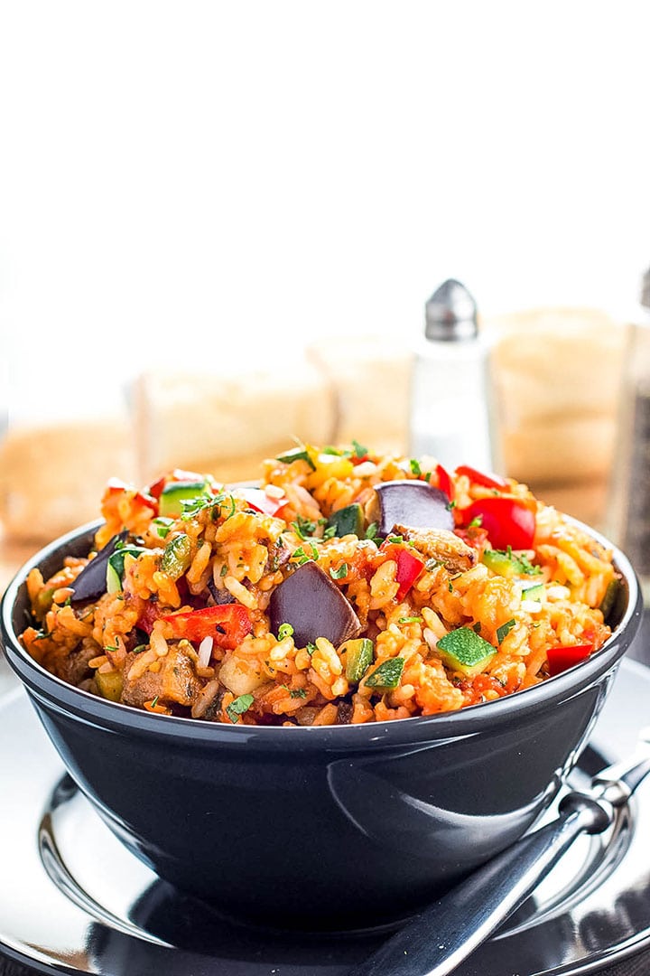 A bowl of Italian style rice in a bowl with salt and pepper mills in the background