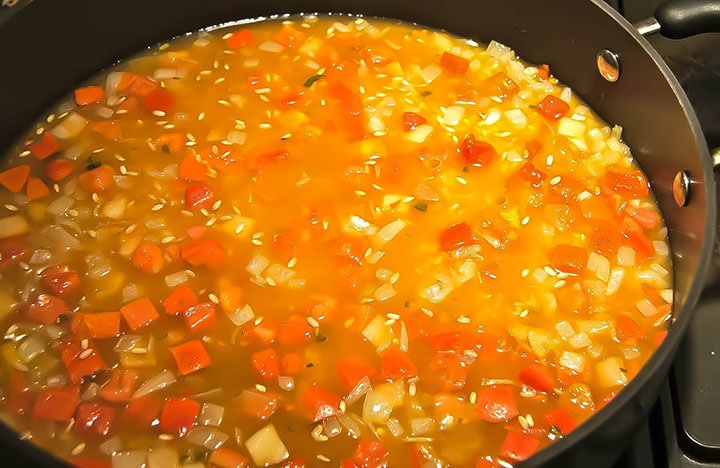 a pan with the stock and tomato mixture cooking with the rice added