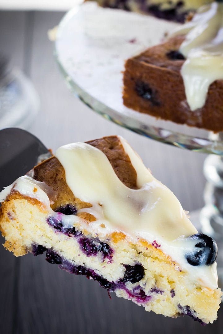 A piece of the Best blueberry cake EVER being cut from the cake