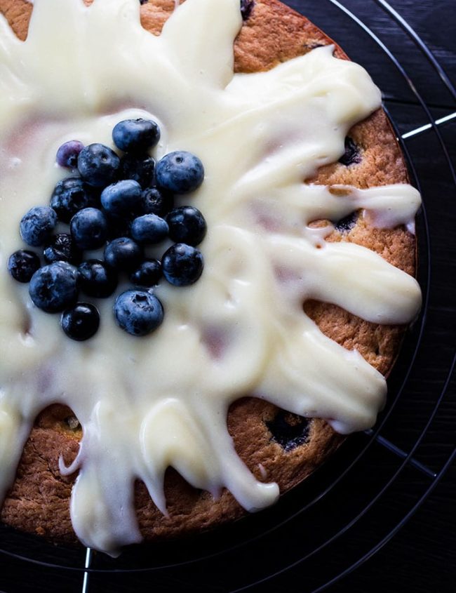 Blueberry cake drizzled with cream cheese icing and topped with some fresh blueberries