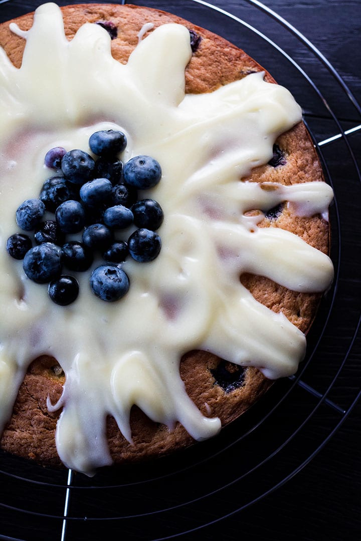 Blueberry cake drizzled with cream cheese icing and topped with some fresh blueberries