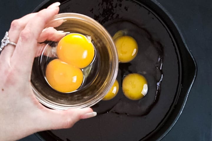 Two egg yolks in a glass bowl over the pot with the chocolate mixture