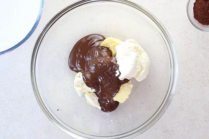 a glass bowl with softened butter, cream cheese and melted chocolate