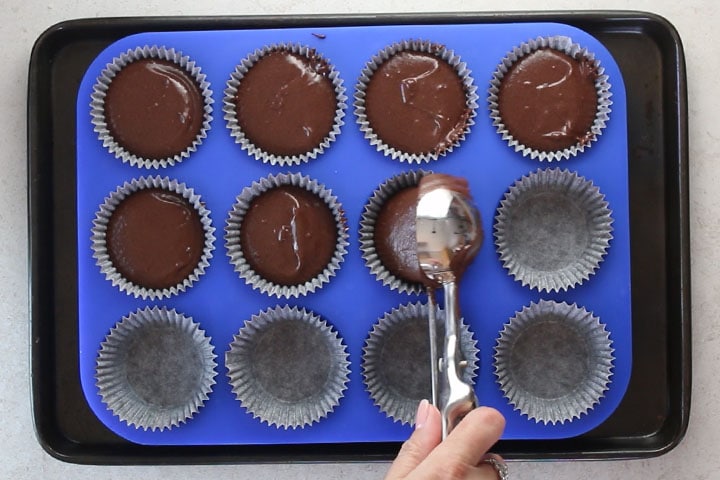 Cake batter being added to a cupcake pan with an ice cream scoop