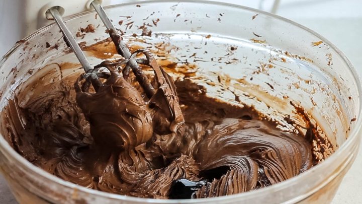 black food coloring being added to the Dark Chocolate Frosting 