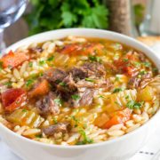 a big bowl full of Slow Cooker Oxtail Orzo Soup sprinkled with fresh parsley