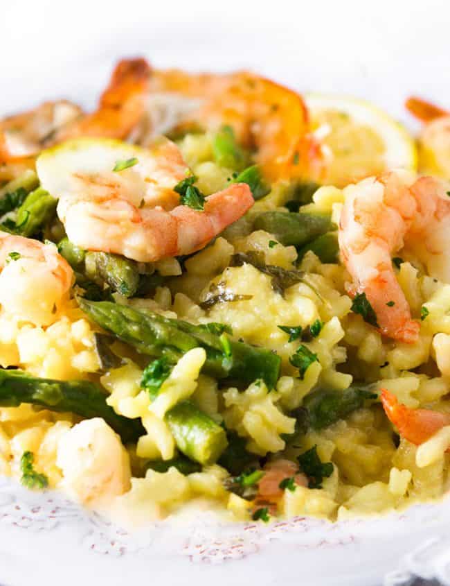 A dish piled high with yellow rice, asparagu and plump shrimp