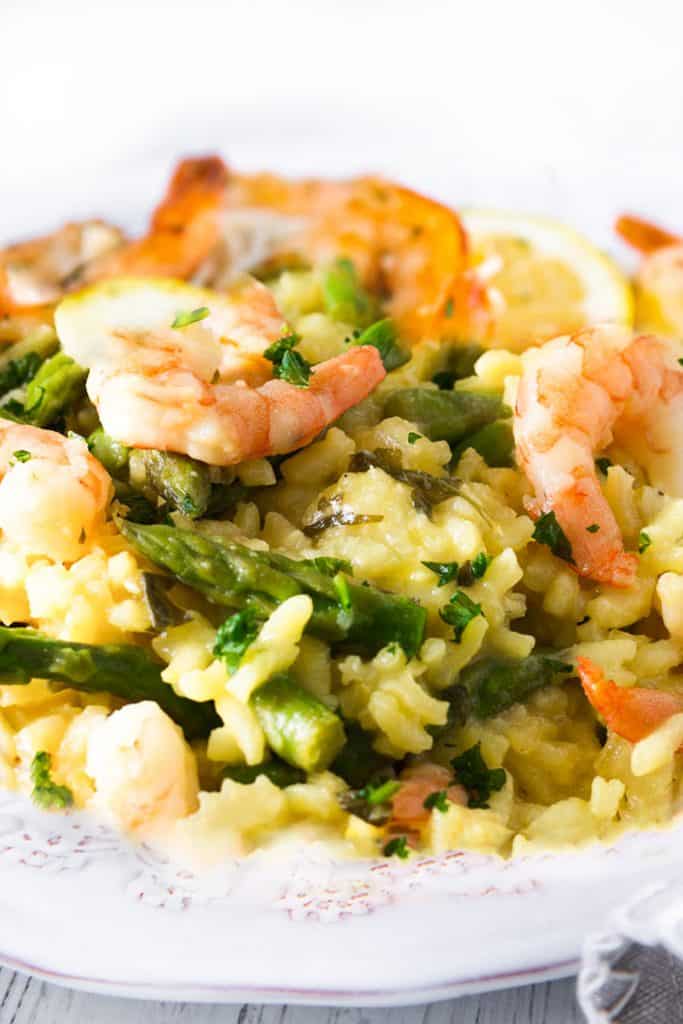 A dish piled high with yellow rice, asparagu and plump shrimp