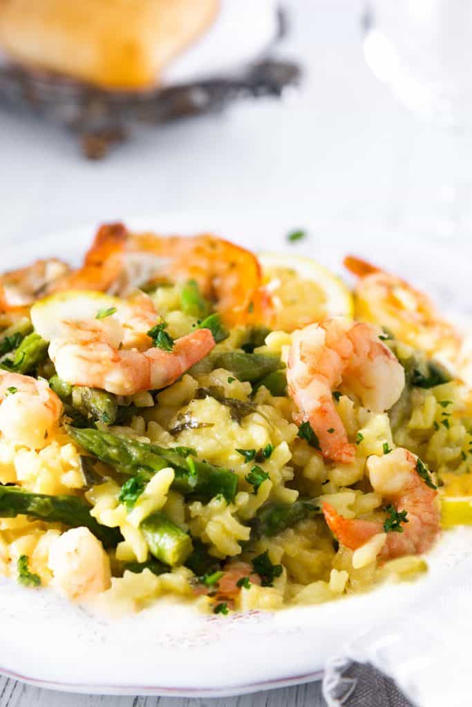 A dish piled high with yellow rice, asparagu and plump shrimp