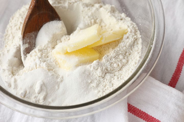 Baking ingredients in a mixing bowl with a wooden spoon on dishcloth