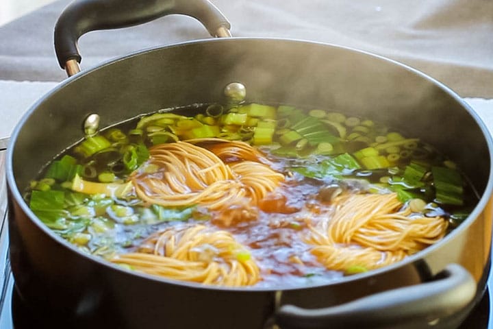 three nests of Chinese noodles added to the pot with the soup