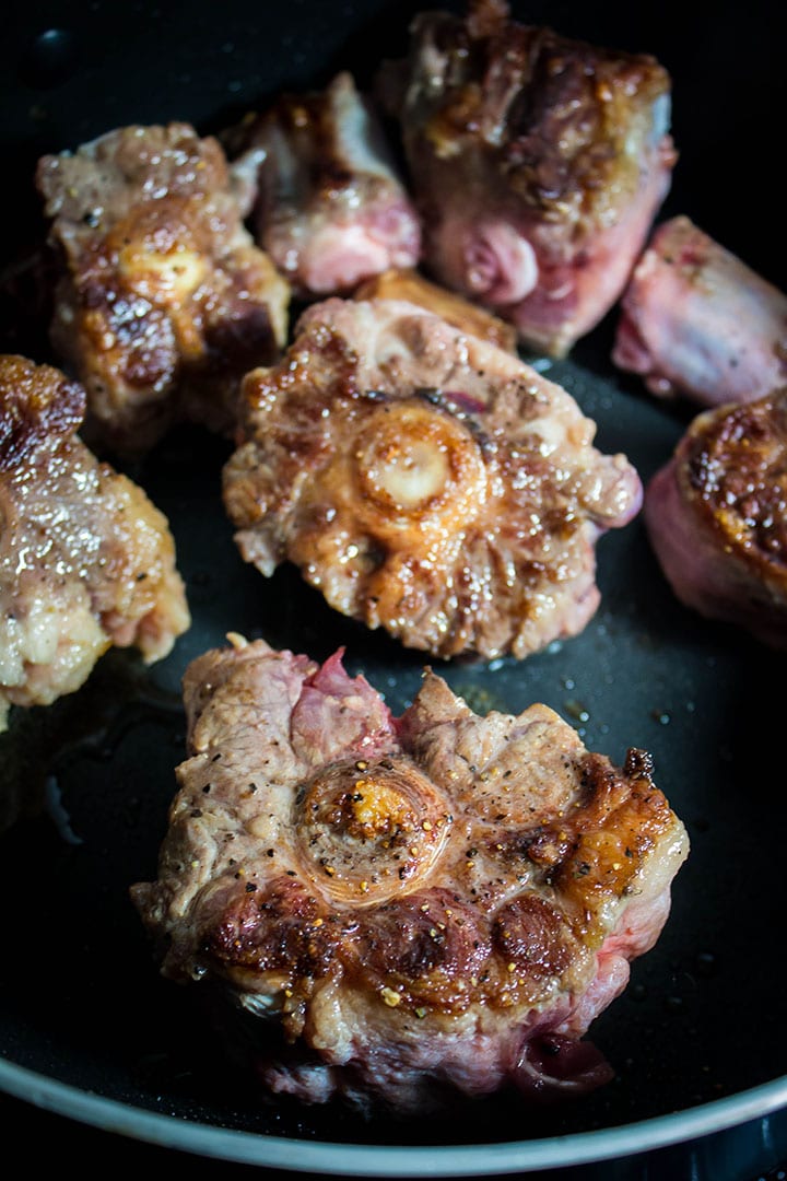 oxtails searing in a frying pan