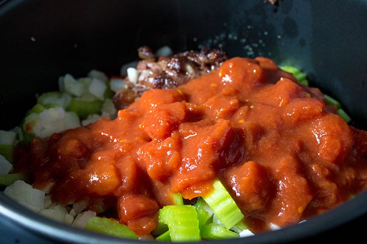 the tomatoes added to the slow cooker with the vegetables and oxtail