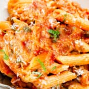 an overhead image of a bowl of pasta alla Norma with a fork and basil leaf
