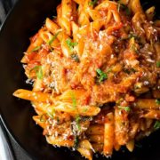 A big plate of Pasta Alla Norma {Pasta with Eggplant Sauce} sprinkled with cheese and scattered with sliced basil
