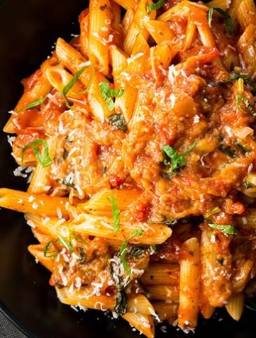 A big plate of Pasta Alla Norma {Pasta with Eggplant Sauce} sprinkled with cheese and scattered with sliced basil