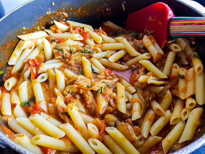 The pasta added to the sauce in the pan