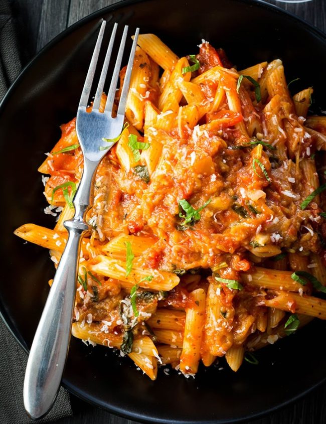 a plate of Pasta with Eggplant Sauce {Pasta Alla Norma} with a dork laying next to it