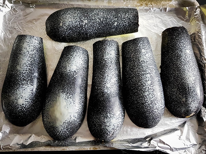The eggplant cut in half in the pan skin side up sprayed with cooking spray