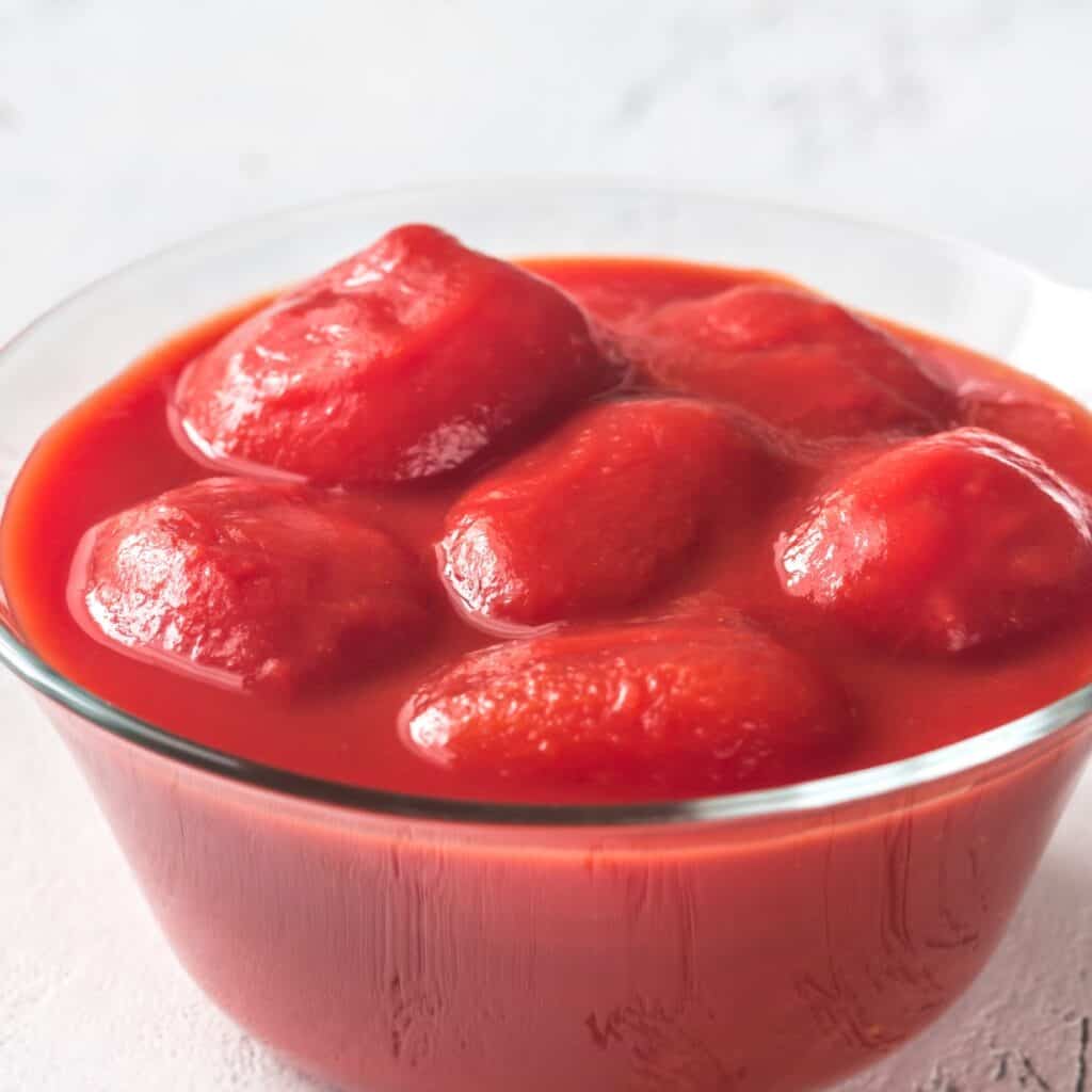 a glass bowl full of canned whole tomatoes