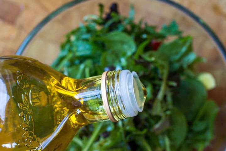 the olive oil being poured into the salad