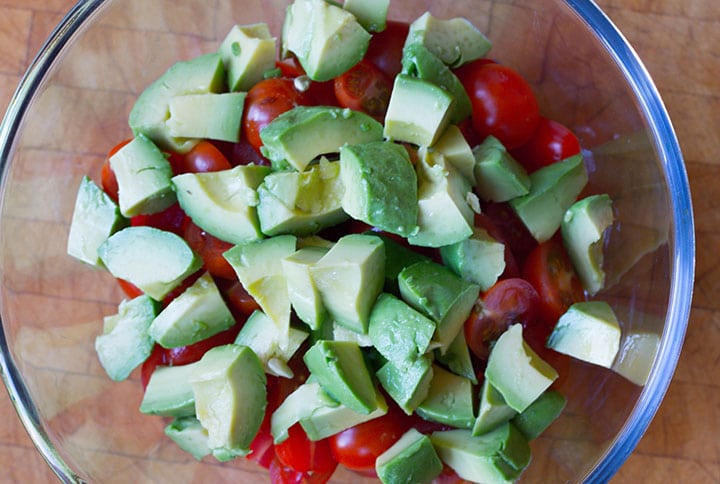 The avocado added to the salad bowl with the tomatoes