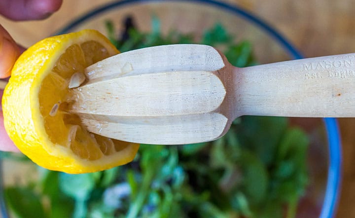 The lemon being juiced over the salad