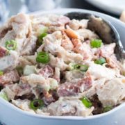 The chicken salad mixed together in a bowl scatted with green onions.