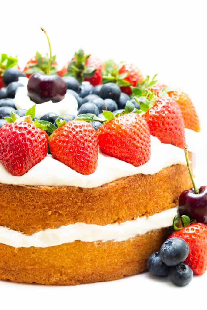 A layer cake topped with cream and fruit