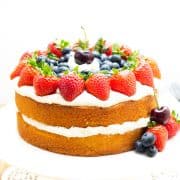 A layer cake on a cake stand topped with cream and fruit